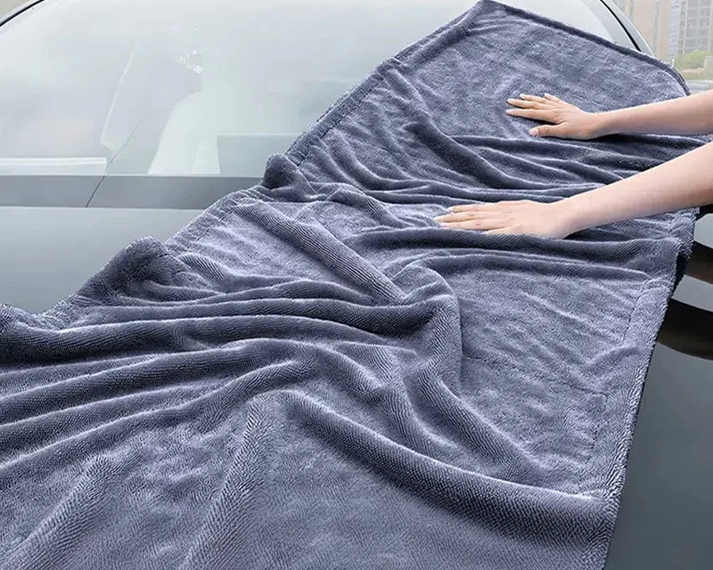 Toalha de microfibra automotiva extra grande 160x60cm sendo usada para secagem completa da lataria do carro, com alta absorção e material macio que não risca a pintura.
